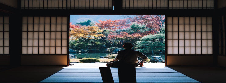 person sitting at threshold of Tatami room, staring out at trees