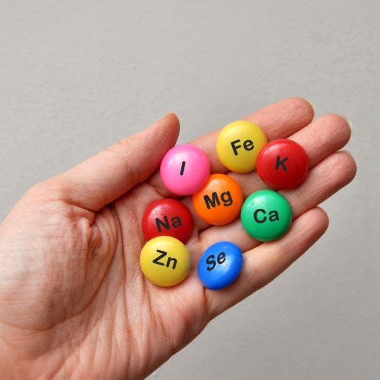 chand holding colored pills labelled with mineral symbols