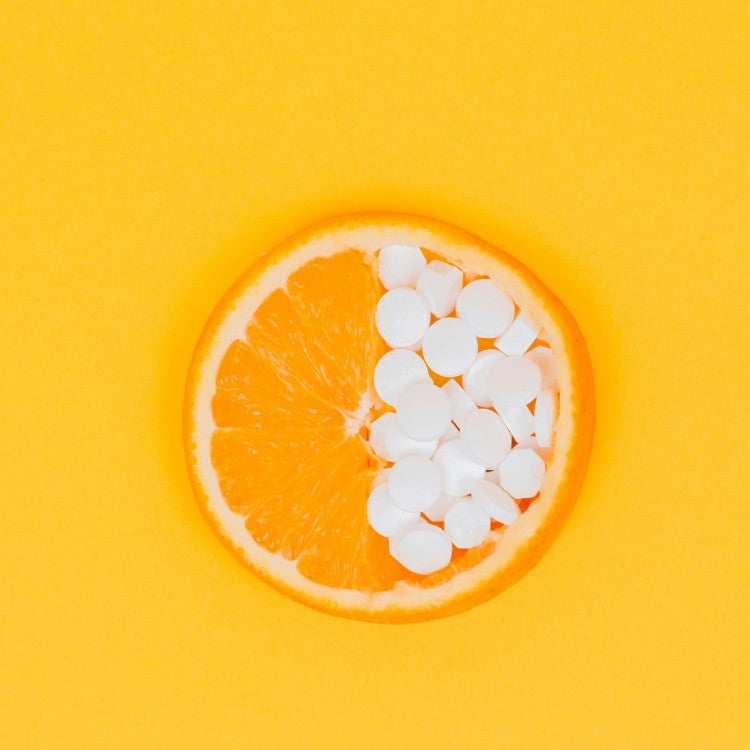 half an orange with white tablets on it