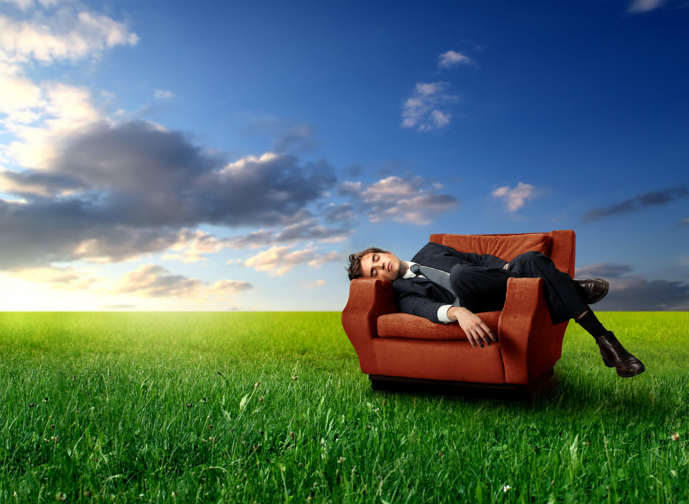man asleep on chair in a field