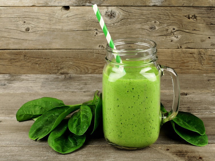 green drink in glass with straw and green leaves