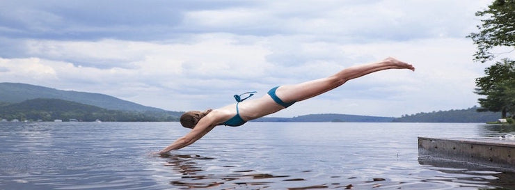 bikini-clad woman diving into lake
