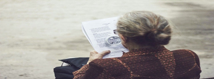 old woman reading a document with magnifying glass