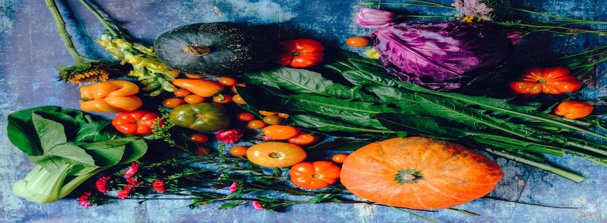 selection of colourful vegetables on a table including pumpkin, peppers and tomatoes