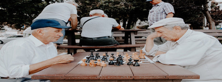 Two elderly men staring across a chess board at one another