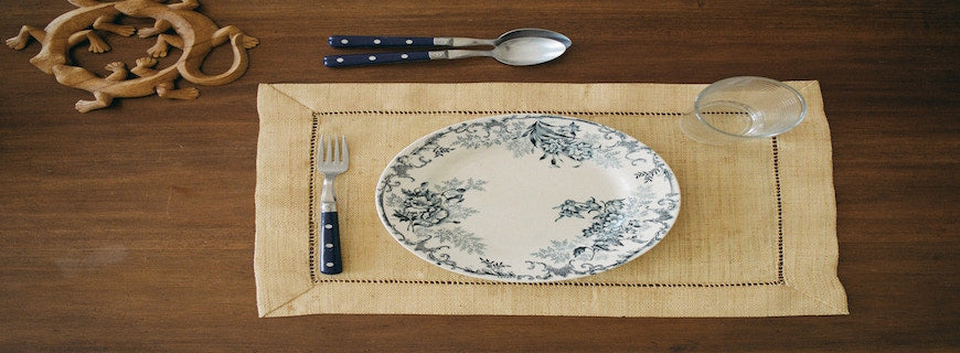 An empty plate on a place mat, with cutlery arranged alongside and above it