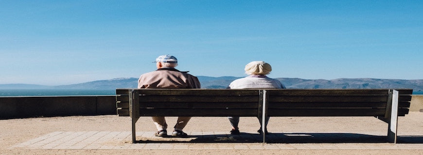 Elderly man and women sat on a bench facing mountains