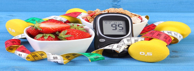 Glucose meter surrounded by fruit, dumbbell, measuring tape