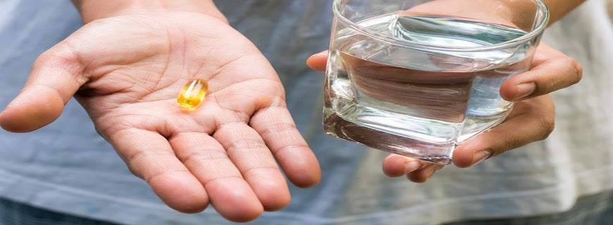 person holding fish oil capsule in the palm of their hand