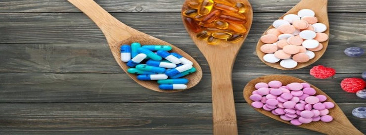 array of pills and capsules on wooden spoons