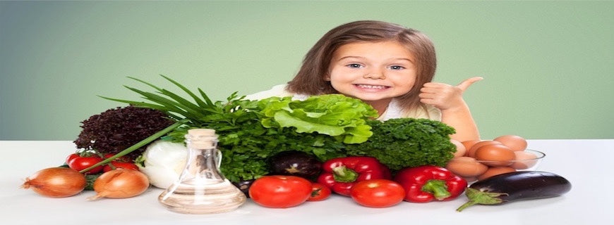 smiling child gives thumbs up in front of table of vegetables