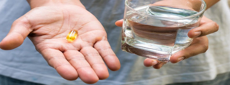 person holding fish oil capsule in palm of their hand