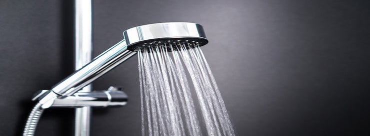 Water running from shower head in bathroom with dark black background. Simple stylish and modern Scandinavian home interior design.