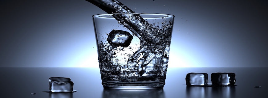 glass of water with ice cubes alongside