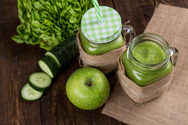 an apple and two green drinks on table