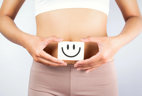 woman holding smiley face over stomach