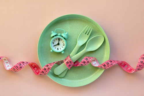green plate fork and spoon with tape measure and alarm clock