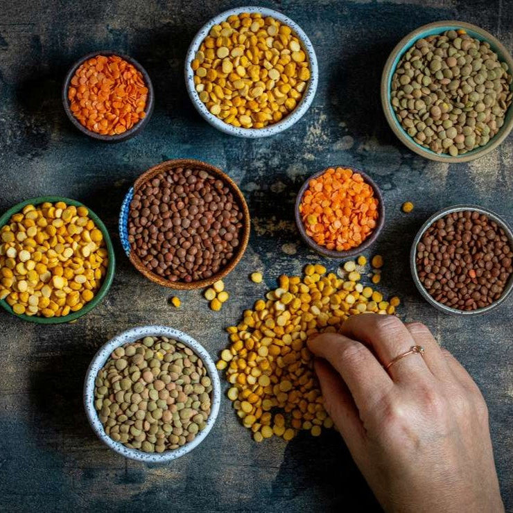Array of vegan food, veggie protein sources: Tofu, vegan milk, beans, lentils, nuts, soy milk, spinach and seeds. Top view on white table.