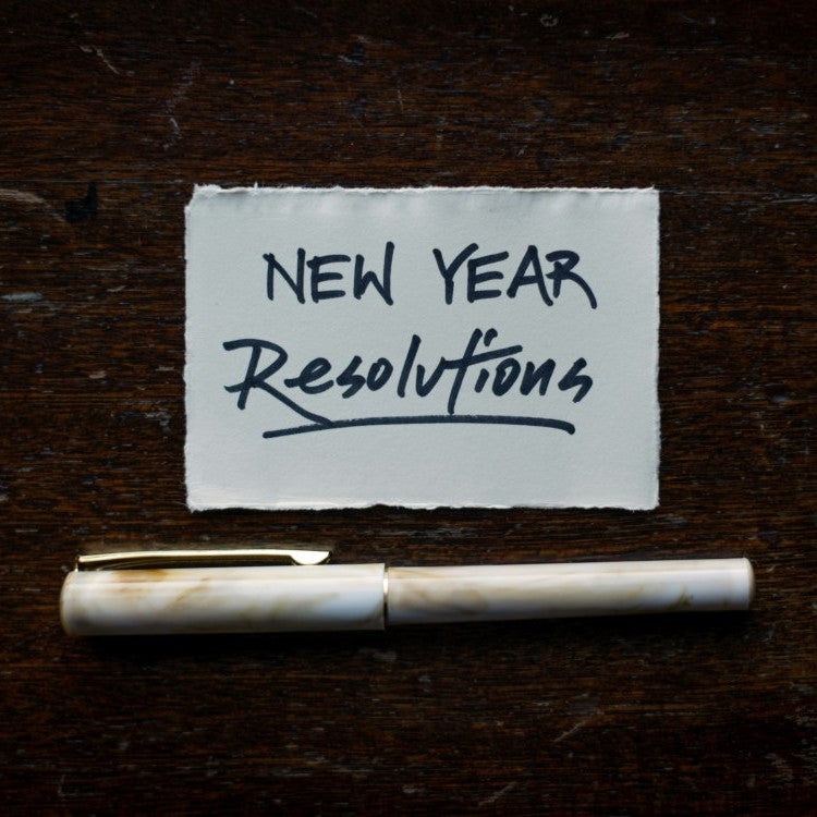 pen and paper with new year resolutions written on it
