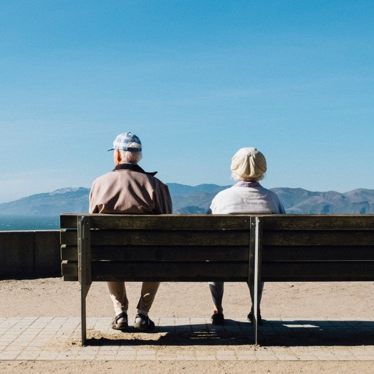 Elderly man and women sat on a bench facing mountains