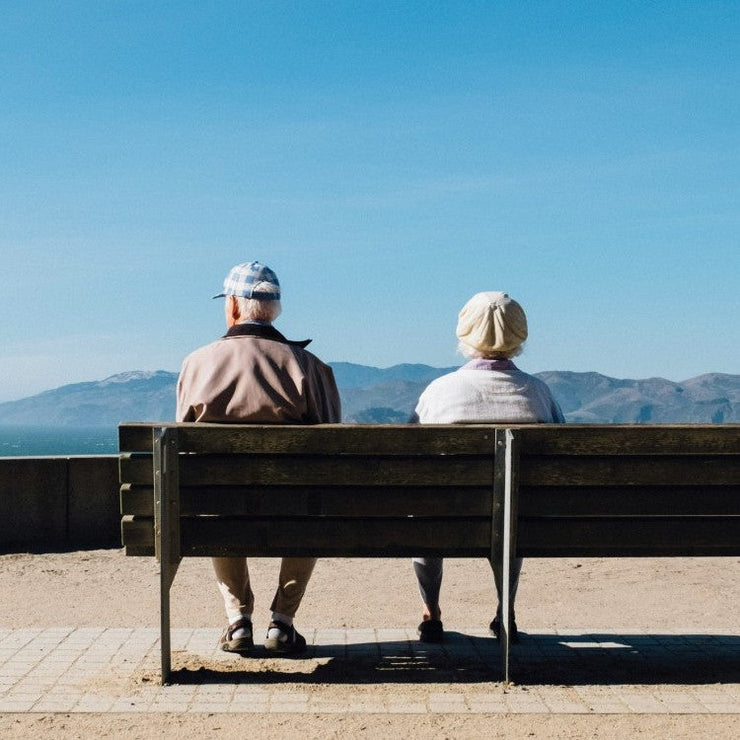 Elderly man and women sat on a bench facing mountains