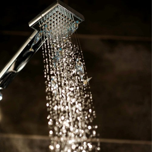 Water running from shower head in bathroom with dark black background. Simple stylish and modern Scandinavian home interior design.