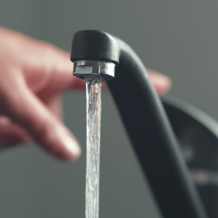 hand holding glass being filled from tap