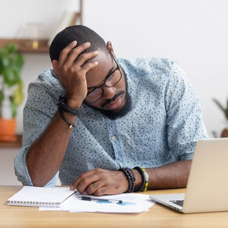 man at desk holding head